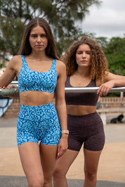 Two women in athletic wear standing outdoors with a metal bar.